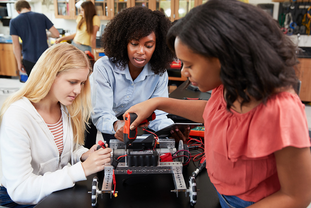 Teacher With Female Pupils Building Robotic Vehicle In Science L